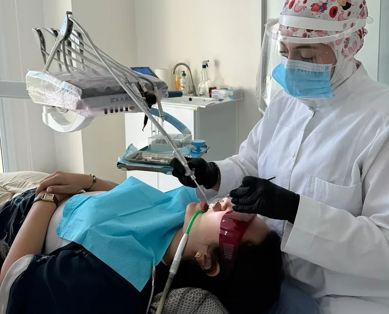 La Dr Wiam Bouziane réalisant un soin sur une patiente, au fauteuil